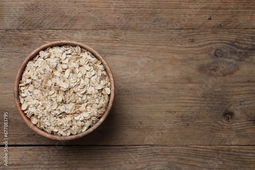 Bowl of oatmeal on wooden table, top view. Space for text