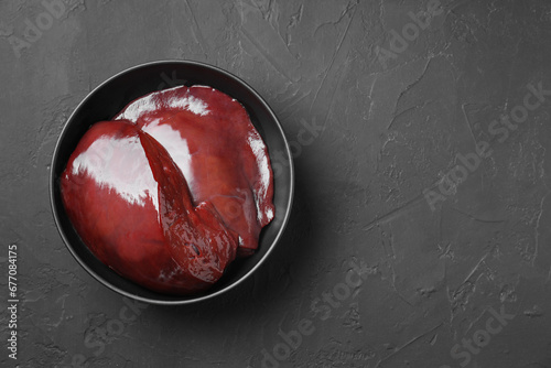 Pieces of raw beef liver in bowl on black table, top view. Space for text