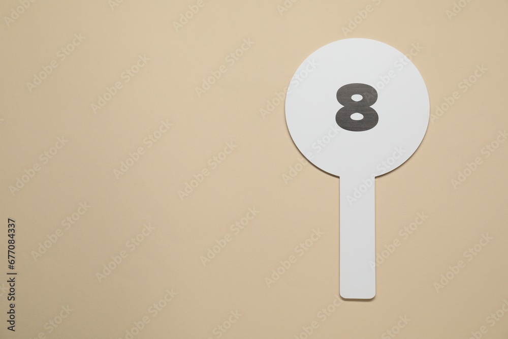 Auction paddle with number 8 on beige background, top view. Space for text Auction paddle with number 8 on beige background, top view. Space for text