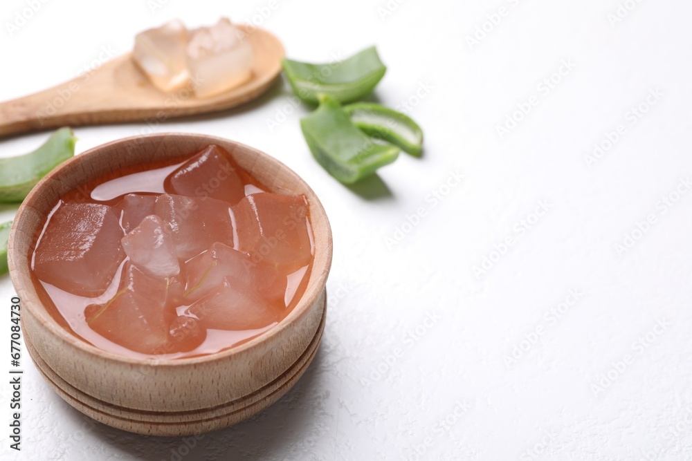 Aloe vera gel and slices of plant on white background, closeup. Space for text