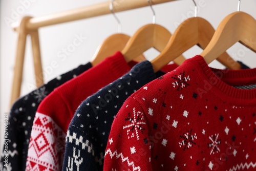 Rack with different Christmas sweaters on light background, closeup