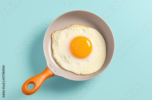 Above view with a sunny side up egg in an iron cast pan on a colored table. Cooking pan with a single fried egg on a colorful background.