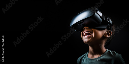 Young boy getting experience using VR headset glasses isolated on a black background with copy space photo