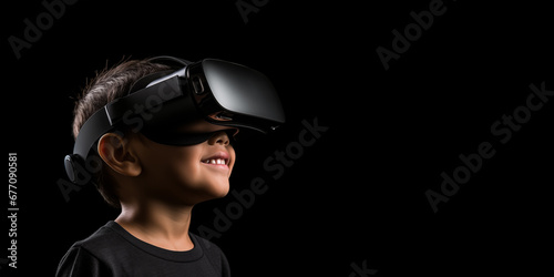Young boy getting experience using VR headset glasses isolated on a black background with copy space © dewaai