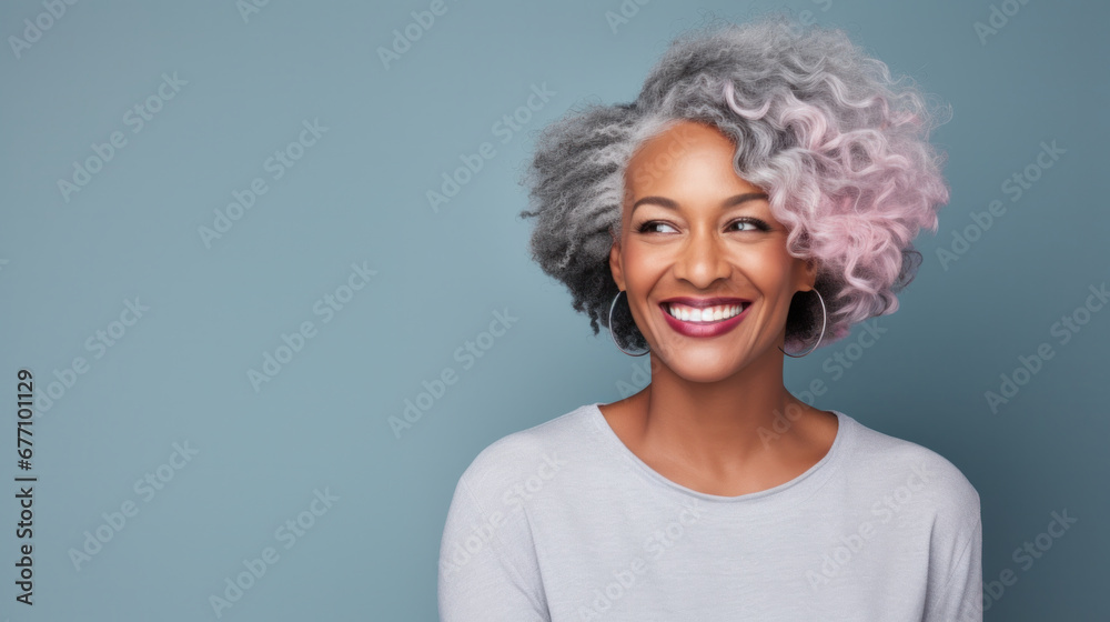 Radiant african american woman with silver and pink hair smiling joyfully on a blue background