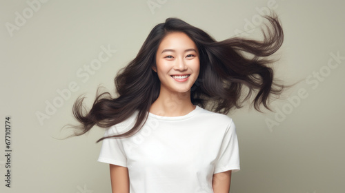 Joyful Asian woman with hair in the wind on a beige background
