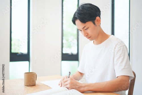 自宅のリビングで資格取得のために勉強する若い男性 photo