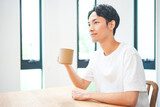 自宅のリビングでコーヒーを飲む若い男性