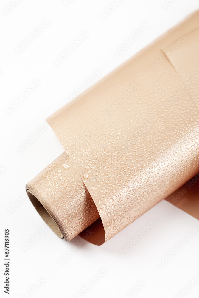 Obraz premium Glossy nude wrapping paper for gifts or flowers with drops of water on white background. Top view