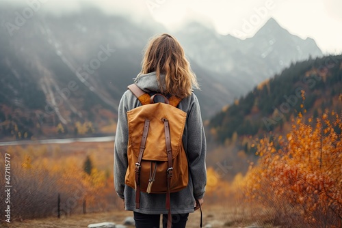 Young woman with backpack enjoying an adventurous hike in nature while admiring the breathtaking view from a mountain peak at sunset. © Iryna