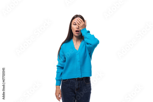 young pretty smiling brunette woman in blue cardigan yawns on white background © Ivan Traimak
