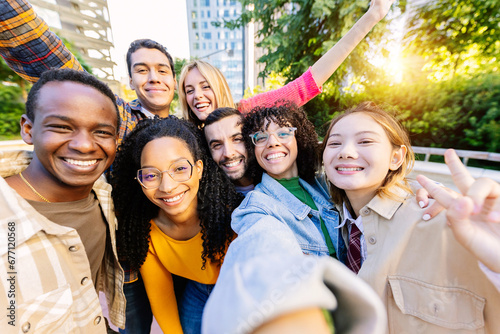 Young community of diverse happy student friends taking selfie portrait together. Millennial group of people having fun enjoying free time outdoors. Youth, diversity and friendship concept.