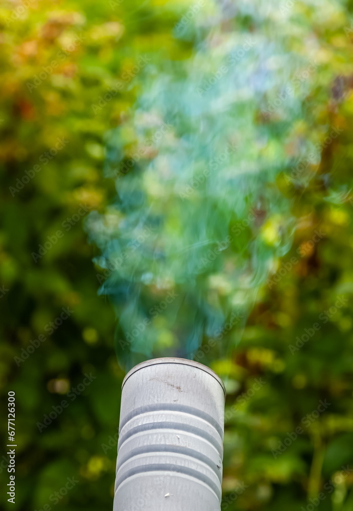 Smoke from a samovar pipe in close-up against the background of greenery in summer Smoke from a samovar pipe in close-up against the background of greenery in summer