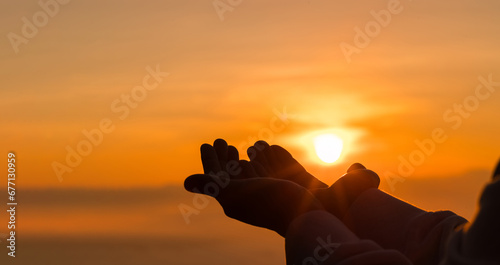 Silhouette of woman kneeling down praying for worship God at sky background. Christians pray to jesus christ for calmness. In morning people got to a quiet place and prayed. copy space.