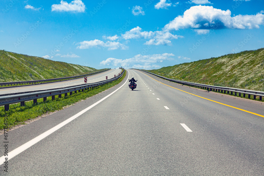 highway track with road markings and biker. summer asphalt road under a blue cloudy sky.