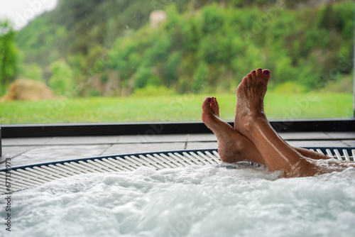 Feet in a jacuzzi in a winter scene in vacations in resort. Wellness and therapeutic relaxation in a spa in the mountains.