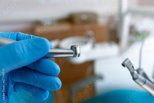 A dentist in blue nitrile medical gloves holds a dental handpiece. photo