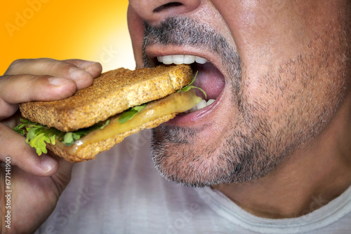 Irresistible craving for junk food. Close-up of a hungry man biting into a cheese toast.