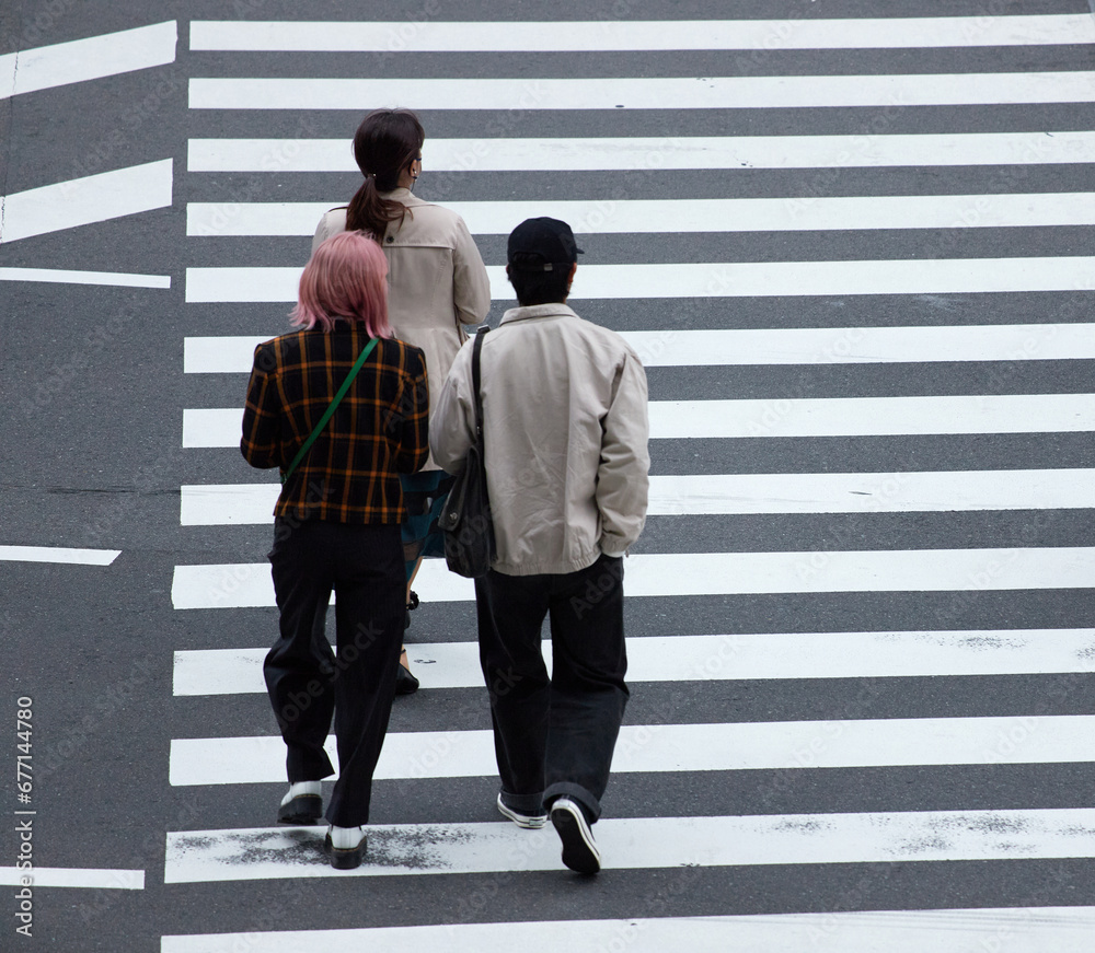 Obraz premium 都市の交差点の横断歩道を渡る若者たちの姿
