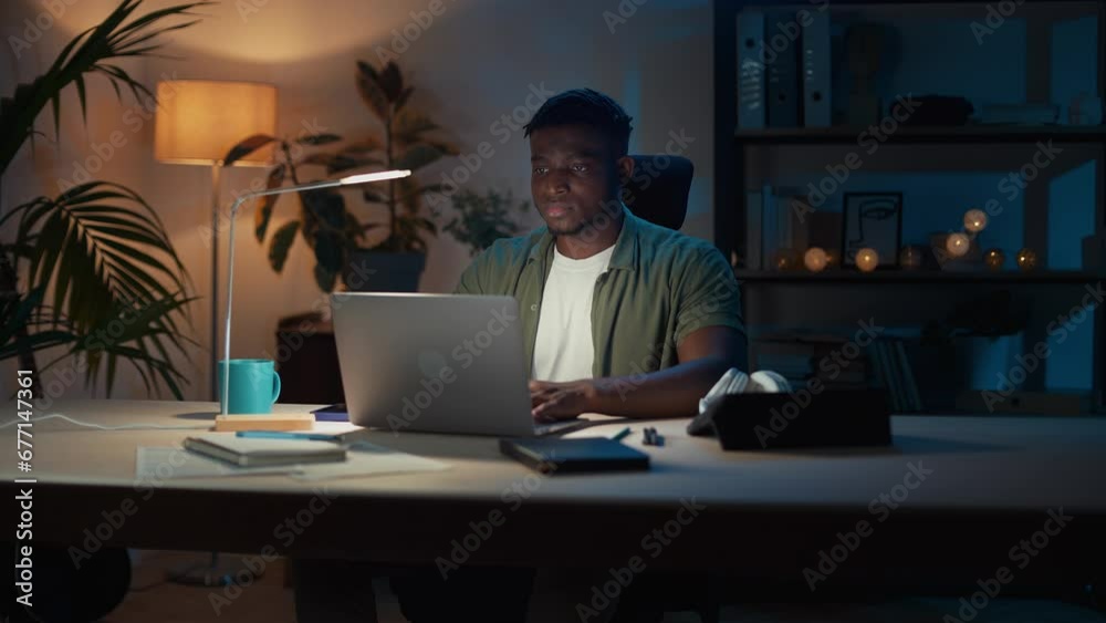 Pensive african man using laptop for remote work in evening Pensive african man using laptop for remote work in evening