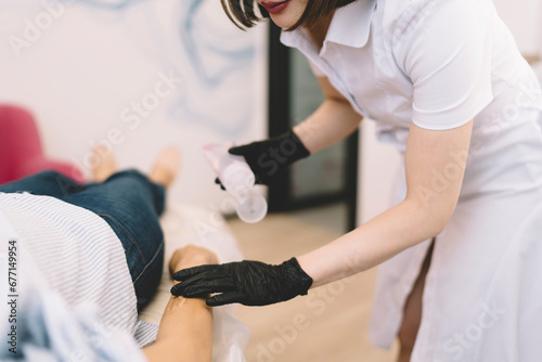 Unrecognizable beautician putting gel on client in salon
