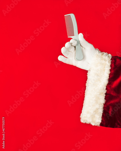 Santa Claus holds a comb in his hand. Hair care concept, hair salon, etc. Red background, with  copy space.
