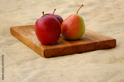 Fruits on a wooden cutting board - two red apples and a pear