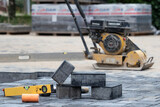 Construction site with paving slabs, a level and a construction machine