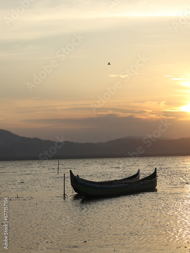 Boat in the lake at sunset. Rowing boat floating over the Limboto Lake waters. Gorontalo, Indonesia