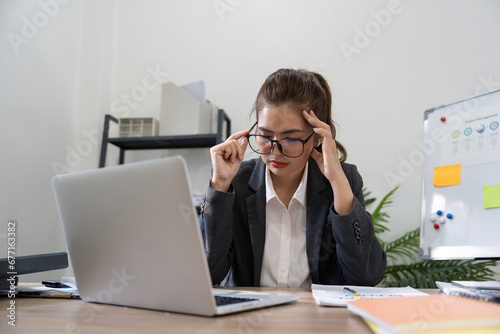 Business asian women are stress while working on laptop, Tired business woman with headache at office, feeling sick at work photo