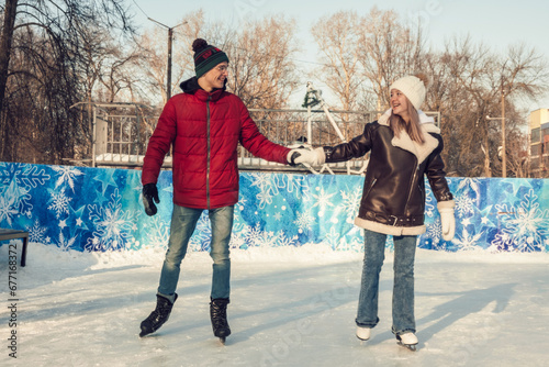 Young couple in love have fun, active date ice skating on the ice rink on a winter day.Winter entertainment,leisure activity,Valentine's day.