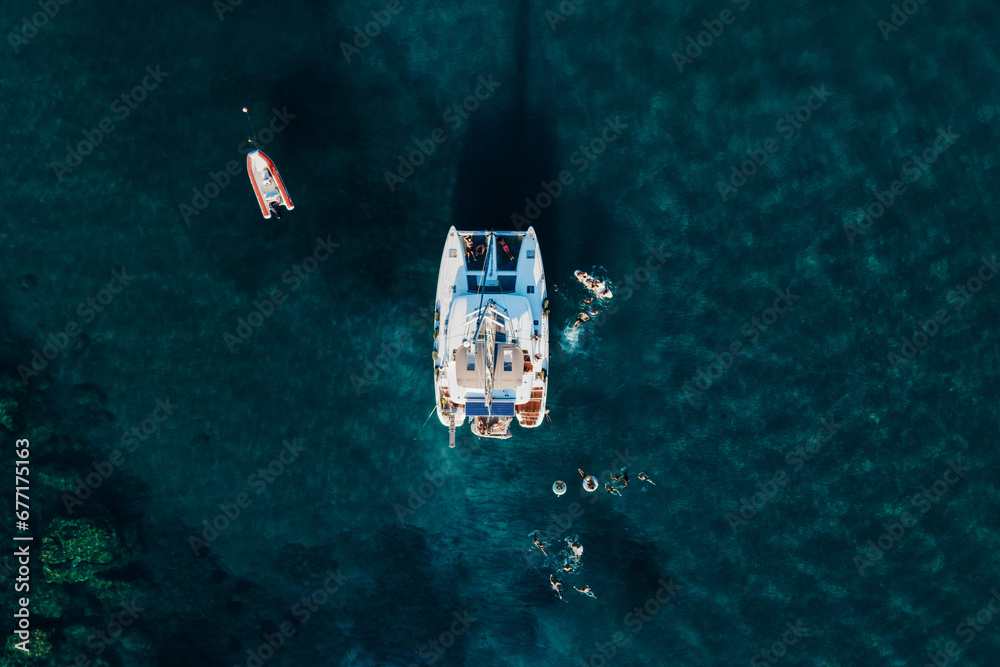 Amazing top view of Catamaran anchored in blue sea in summer. Travel background. Cruise vacation. Amazing top view of Catamaran anchored in blue sea in summer. Travel background. Cruise vacation.