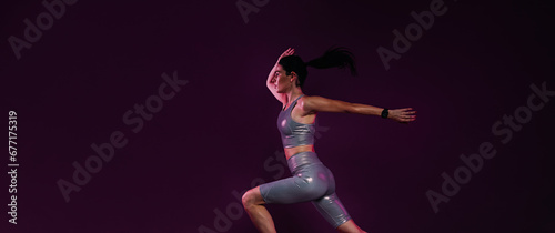 Fotografi Side view of young female sprinting over a magenta backdrop
