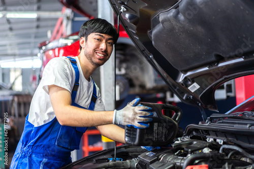 Professional car technician mechanic man in uniform work fixing vehicle car engine and maintenance repairing checking under the car hood in auto service. Automobile service garage