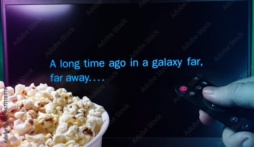 Fototapeta premium Kyiv. Ukraine. 10.11.2023: Person watching Star Wars movie with popcorn and remote control. A long time ago in a galaxy far, far away. Stock editorial photo.