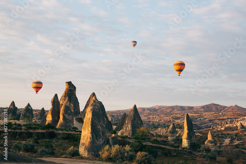 Balloons float past towering fairy chimneys of Cappadocia, with golden sunlight illuminating the unique landscape