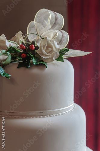 Ribbon and flowers on the top of a white iced wedding cake.