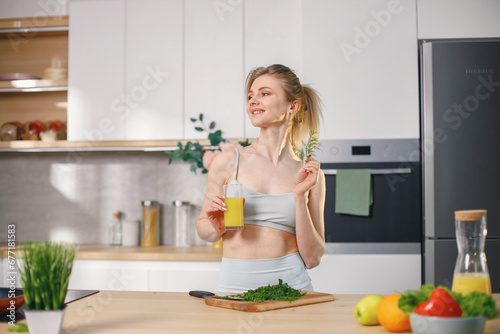 Fit woman on a kitchen chopping a fresh healthy vegetables and drink a juice