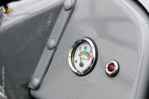Closeup of an oil temperature guage and warning light on a grey vintage Massey Ferguson farm tractor photo