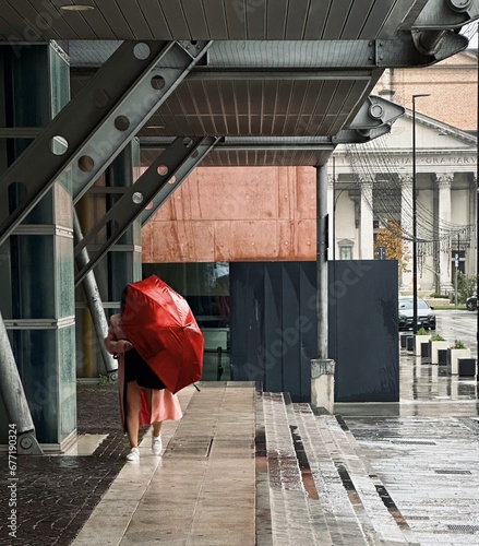 Ragazza con ombrello rosso sotto la pioggia che passeggia photo