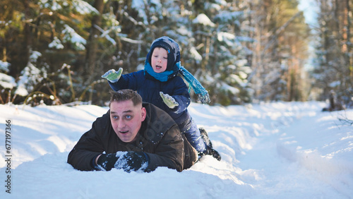 A father and his young son playing in the winter woods.