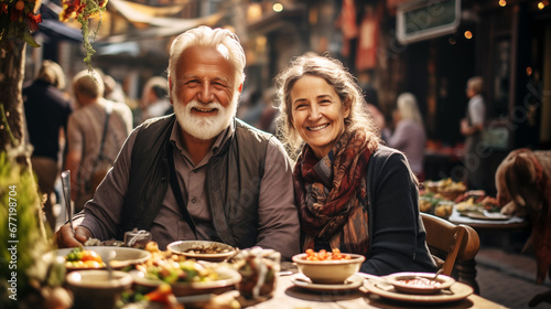 Photo of A cheerful elderly couple participate in a Turkish feast with an abundance of traditional Turkish cuisine  Turkish sweets  with cups of tea  in a small Turkish street