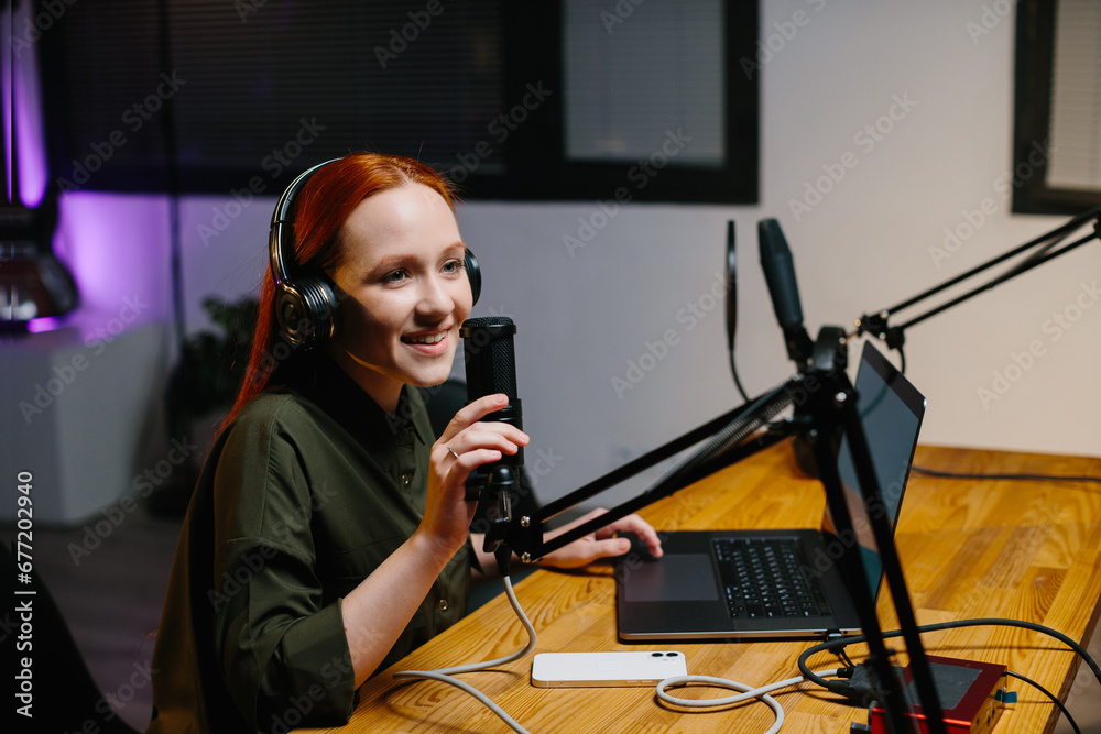 The girl radio presenter speaks into the microphone during the broadcast at the radio station. Online blogger during the stream. The girl radio presenter speaks into the microphone during the broadcast at the radio station. Online blogger during the stream.