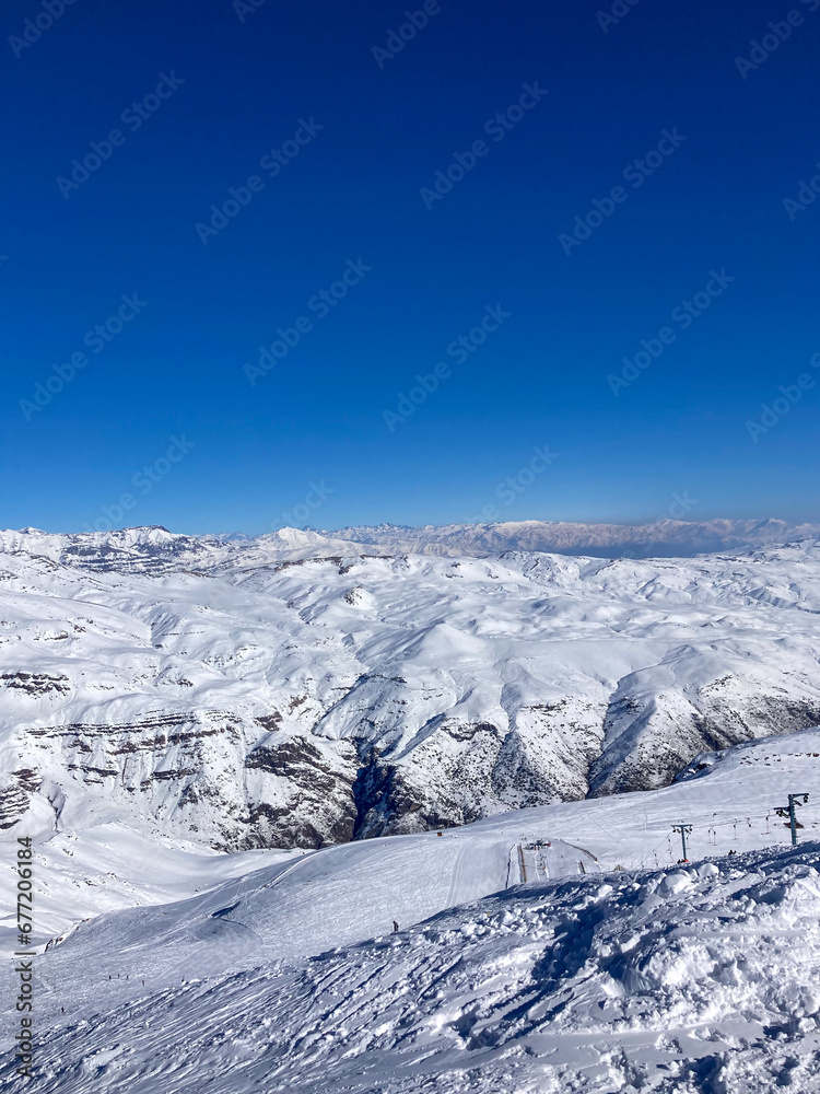 Panoramic view of a majestic snow-covered mountain at a ski resort, with slopes ready for action.