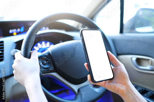 Mockup of woman driver hand using blank white screen mobile smart phone inside a car, searching location via gps navigator application. photo