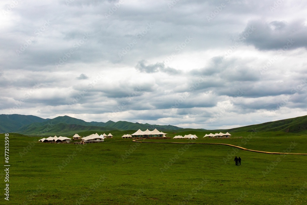 Green landscape and mountains with white tent houses placed on the meadow Green landscape and mountains with white tent houses placed on the meadow