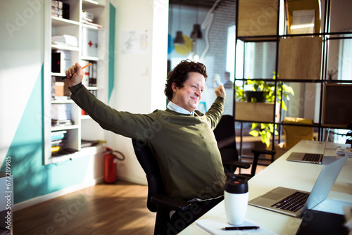 Businessman stretching arms after long day in office photo