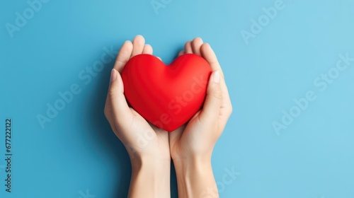 hands hold a red heart on a blue background 