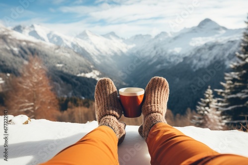Feet in woollen socks by the Alps mountains view. Woman relaxes by mountain view with a cup of hot drink. Close up on feet. Winter and Christmas holidays concept photo