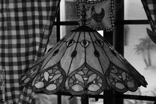 A vintage lantern and windows with curtains in the background, in grayscale
